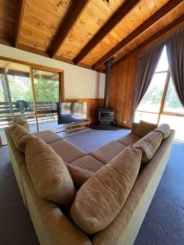 a large couch in a living room with windows at Howqua Haven in Howqua