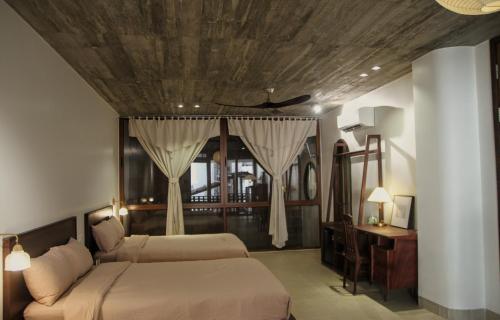 a bedroom with two beds and a wooden ceiling at Komi Homestay in Hue