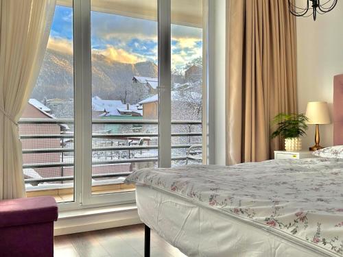 a bedroom with a large window with a mountain view at Central Premium Apartment in Braşov