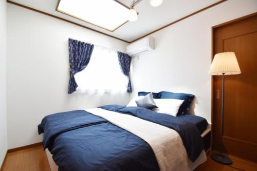 een slaapkamer met een blauw en wit bed en een lamp bij OMOTENASHI in Kyoto