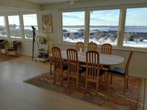 een eetkamer met een tafel, stoelen en ramen bij Cozy Summerhouse With Spectacular Views! in Ølsted