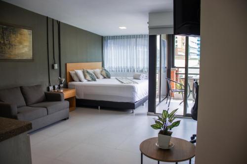 a bedroom with a bed and a couch and a table at Hotel Bambu Milla De Oro in Medellín