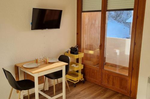 Zimmer mit einem Tisch, Stühlen und einem TV in der Unterkunft Le Montagnard in Mijoux