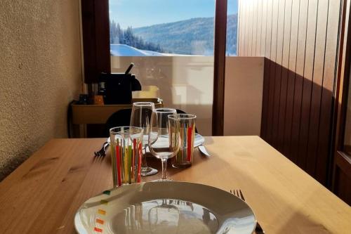 una mesa con copas de vino y un plato en ella en Le Montagnard, en Mijoux