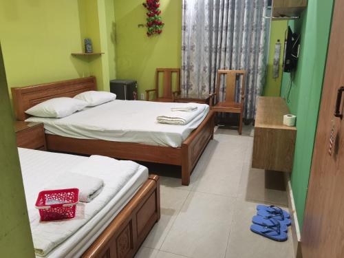 a bedroom with two beds and two blue shoes on the floor at MOTEL WIN - PHÁT in Bien Hoa