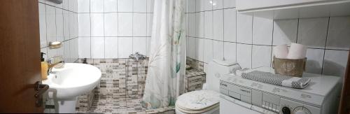 Baño blanco con aseo y lavamanos en Daphne's apartment en Kavala