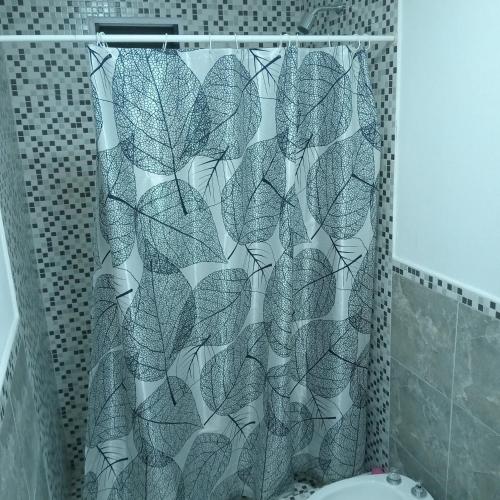 a shower curtain with a leaf pattern in a bathroom at Acogedor y familiar departamento c est in Santiago del Estero