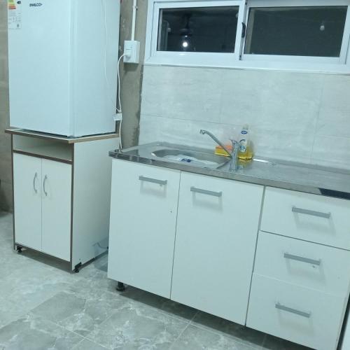 a kitchen with white cabinets and a sink at Acogedor y familiar departamento c est in Santiago del Estero