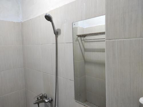 a shower in a bathroom with a mirror at OYO 93411 Syariah Hotel Tomborang in Karema