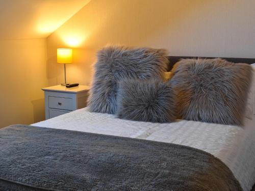 a bedroom with a bed with furry pillows and a lamp at Hugh Cottage in Whitehaven