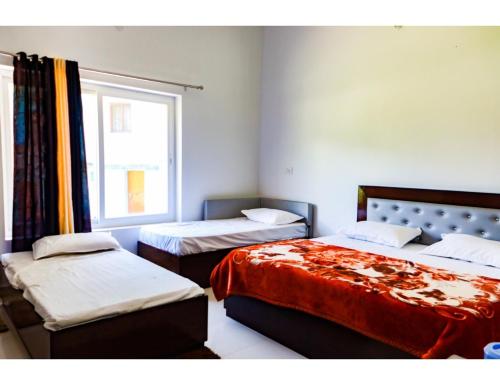 a bedroom with two beds and a window at Hotel Chaar Vedas, Uttarkashi in Uttarkāshi