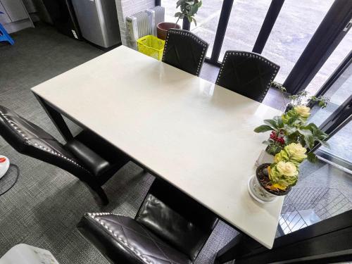 una mesa blanca con sillas negras y flores. en Ho Home Tel, en Seúl