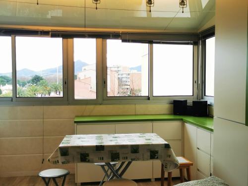 - une cuisine avec une table et quelques fenêtres dans l'établissement Le petit Bois en bord de mer - accès animations, commerce et plage, à Argelès-sur-Mer