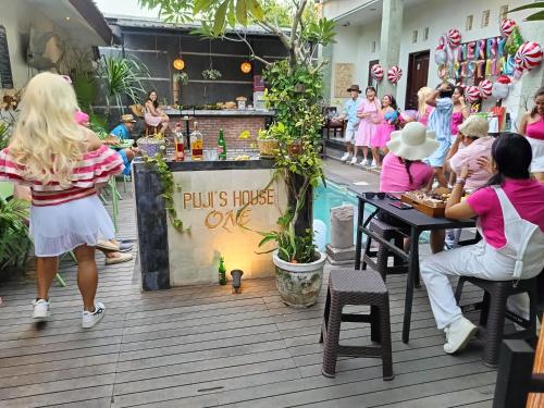 a group of people sitting at tables in a restaurant at Pujihouse One in Legian