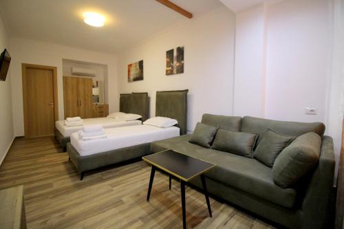 a living room with a couch and two beds at Ortus Rooms in Sarandë