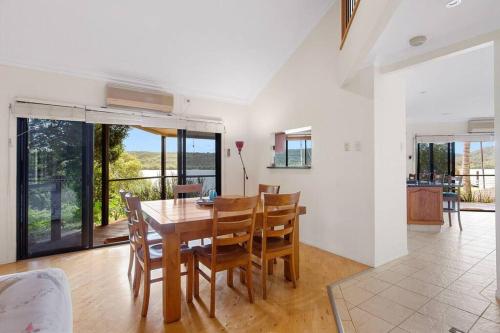 a dining room with a wooden table and chairs at Waterfront, Deep Water Pontoon, views to Straddie in Russell Island