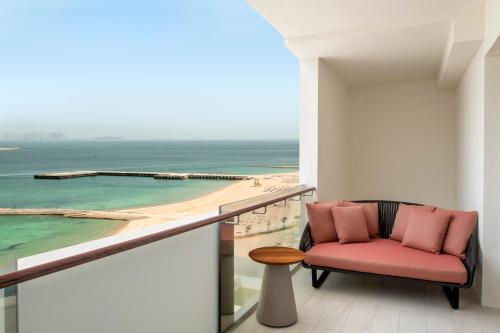 a balcony with a chair and a view of the ocean at Rixos Gulf Hotel Doha in Doha