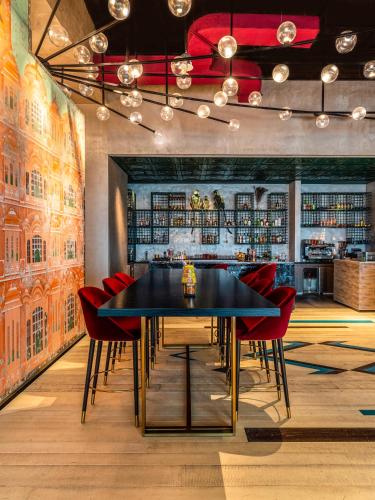 a dining room with a black table and red chairs at Rixos Gulf Hotel Doha in Doha