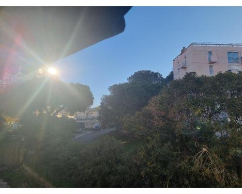 un soleil brille sur une rue avec un bâtiment dans l'établissement Appartement proche plage, à Ajaccio