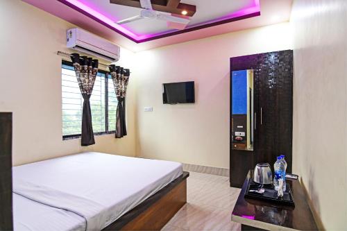 een slaapkamer met een bed en een tv. bij OYO HOTEL FLOWRA in Jangipur