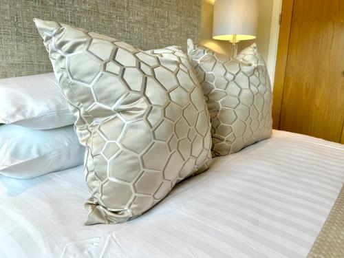 a bed with three pillows and a lamp on it at Superior Apartment In Cardiff City Centre in Cardiff