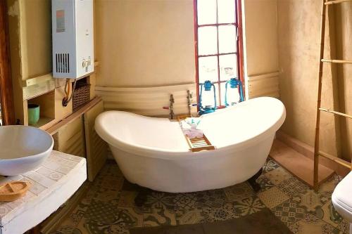 a white bath tub in a bathroom with a window at Farm Stay: Enjoy Fynbos Views & Wood Fired Hot Tub in Hopefield