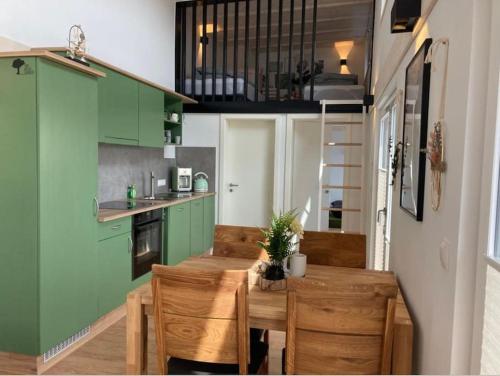 eine Küche mit grünen Schränken sowie einem Holztisch und Stühlen in der Unterkunft Tinyhouse Wald(t)raum in Wilhelmsthal
