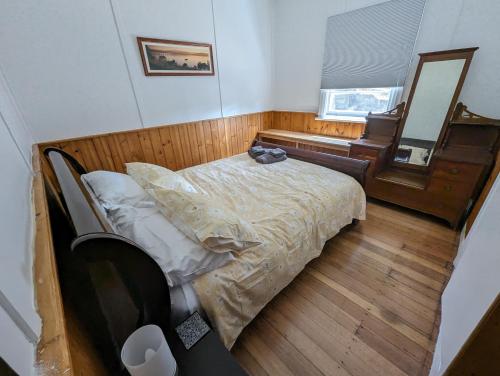 a bedroom with a bed and a mirror and a piano at Lyell Cottage Queenstown Comfortable and Warm in Queenstown
