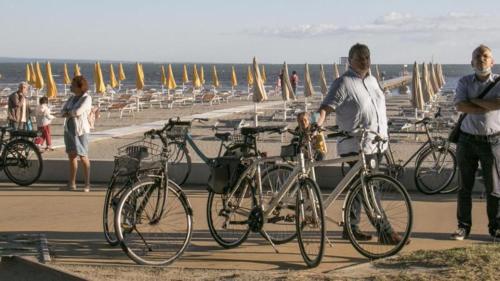 een man die naast fietsen op het strand staat bij Comfy flat with balcony at 30metres from the beach in Lido