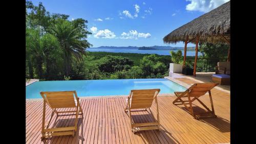 two chairs sitting on a deck next to a swimming pool at Villa Agay in Nosy Be
