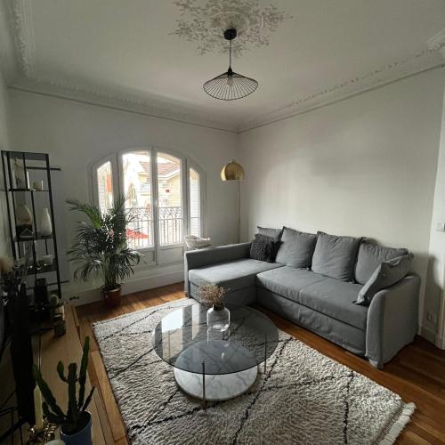 un salon avec un canapé et une table en verre dans l'établissement Appartement cosy & lumineux Montmartre, à Paris