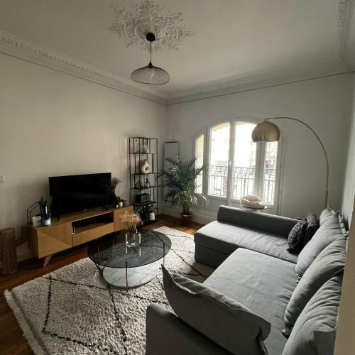 un salon avec un canapé et une table dans l'établissement Appartement cosy & lumineux Montmartre, à Paris