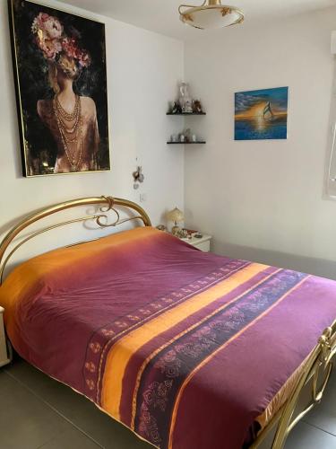 a bed in a room with a painting on the wall at AppartCanet in Canet-en-Roussillon