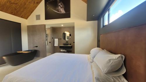 a bedroom with a large bed and a bathroom at Chalet Hills in Sampsons Flat