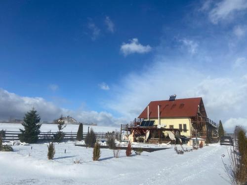 a barn in a snow covered field with a house at Casa Genesini in Miercurea-Ciuc