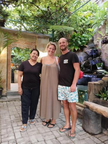 a group of three people standing in front of a fountain at Pujihouse One in Legian