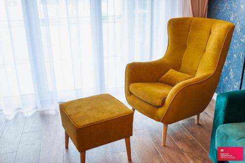 a yellow chair and stool in a living room at The Cozy One in Târgu-Mureş