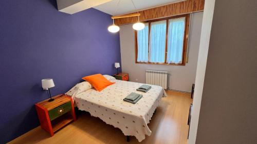 een kleine slaapkamer met een bed met een oranje kussen bij Vivac Jaca in Jaca