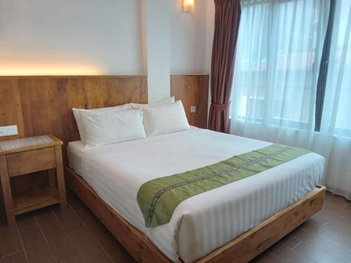 una camera da letto con un grande letto bianco e una finestra di Swiss Hotel Heritage Boutique Melaka a Malacca