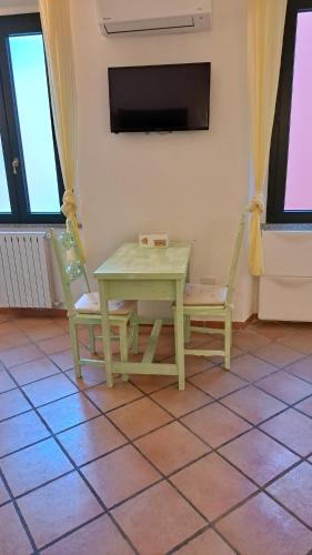 une table verte, deux chaises et une télévision dans l'établissement Villa Liberty, à La Maddalena