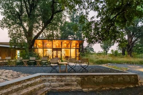 a glass house with a table and chairs at Trees N Tigers, Tadoba in Kolāra