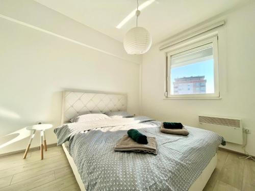ein weißes Schlafzimmer mit einem Bett mit Handtüchern darauf in der Unterkunft Apartman Sunny, Istocno Sarajevo - Lukavica in Sarajevo