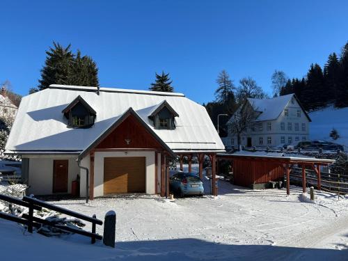 a barn with a car parked in front of a house at HOFBERG Apartmán in Nové Hamry