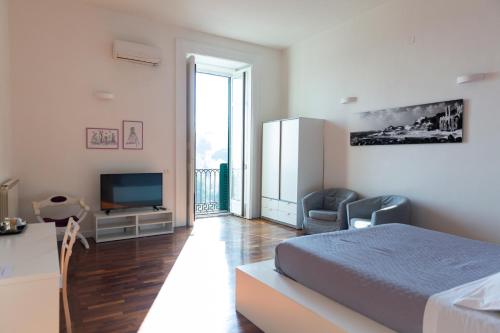 B&B Palazzo Mirelli في نابولي: غرفة نوم بيضاء فيها سرير وتلفزيون