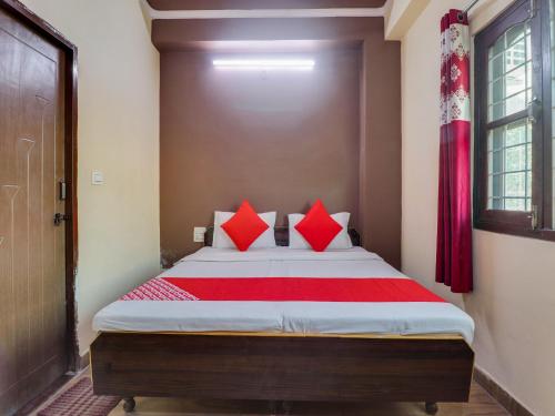 a bedroom with a large bed with red pillows at OYO Hotel Kesariya Bhawan Home Stay in Dehradun