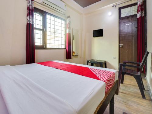 a bedroom with a bed and a chair and a window at OYO Hotel Kesariya Bhawan Home Stay in Dehradun