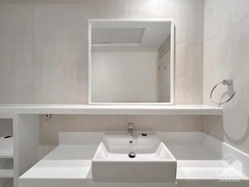 uma casa de banho branca com um lavatório e um espelho em Luxurious 1B Seaview Apartment in JBR em Dubai