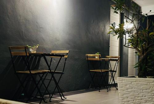 a group of stools against a black wall with plants at CassaKaseh Guest House in Pantai Cenang