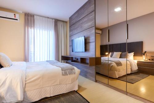 a bedroom with two beds and a tv on the wall at Charlie Top Apart Leblon in Rio de Janeiro