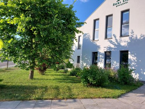 a white house with a tree in the yard at Żabi Staw in Supraśl